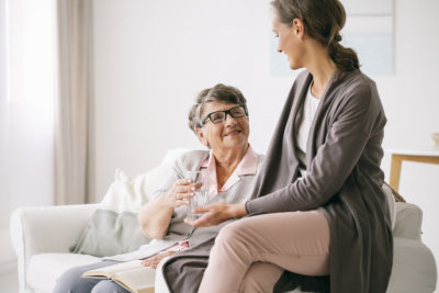 a nurse talking to a senior with glasses