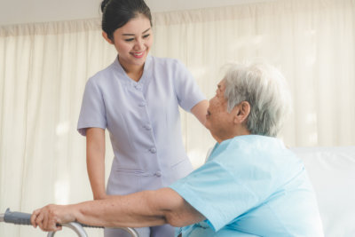 nurse in homecare helping senior patient use walker